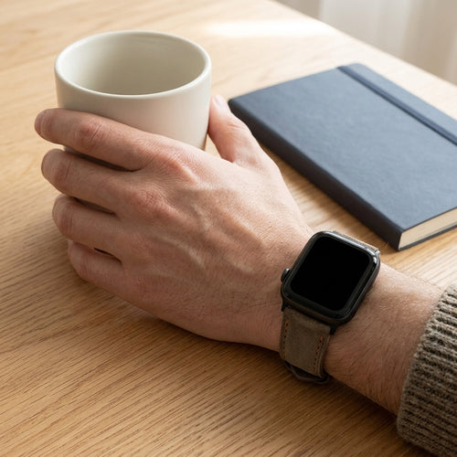 Coffee stitched band worn on a smartwatch beside a coffee cup and notebook