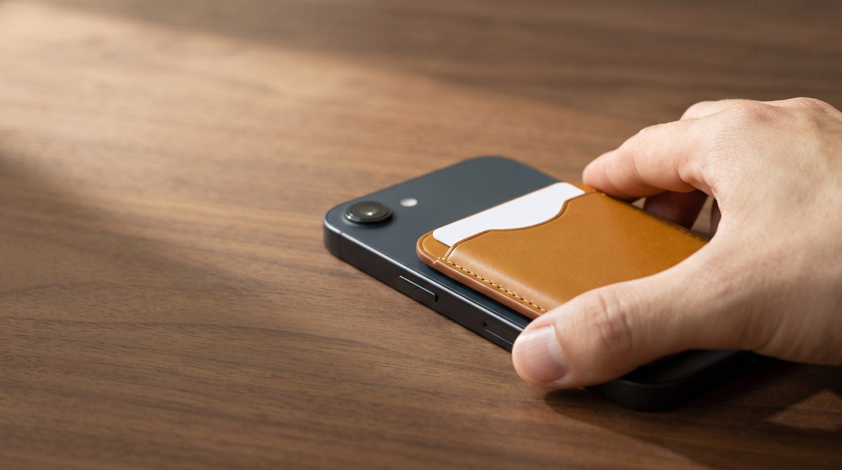 Hand pressing a tan card holder onto the back of a phone