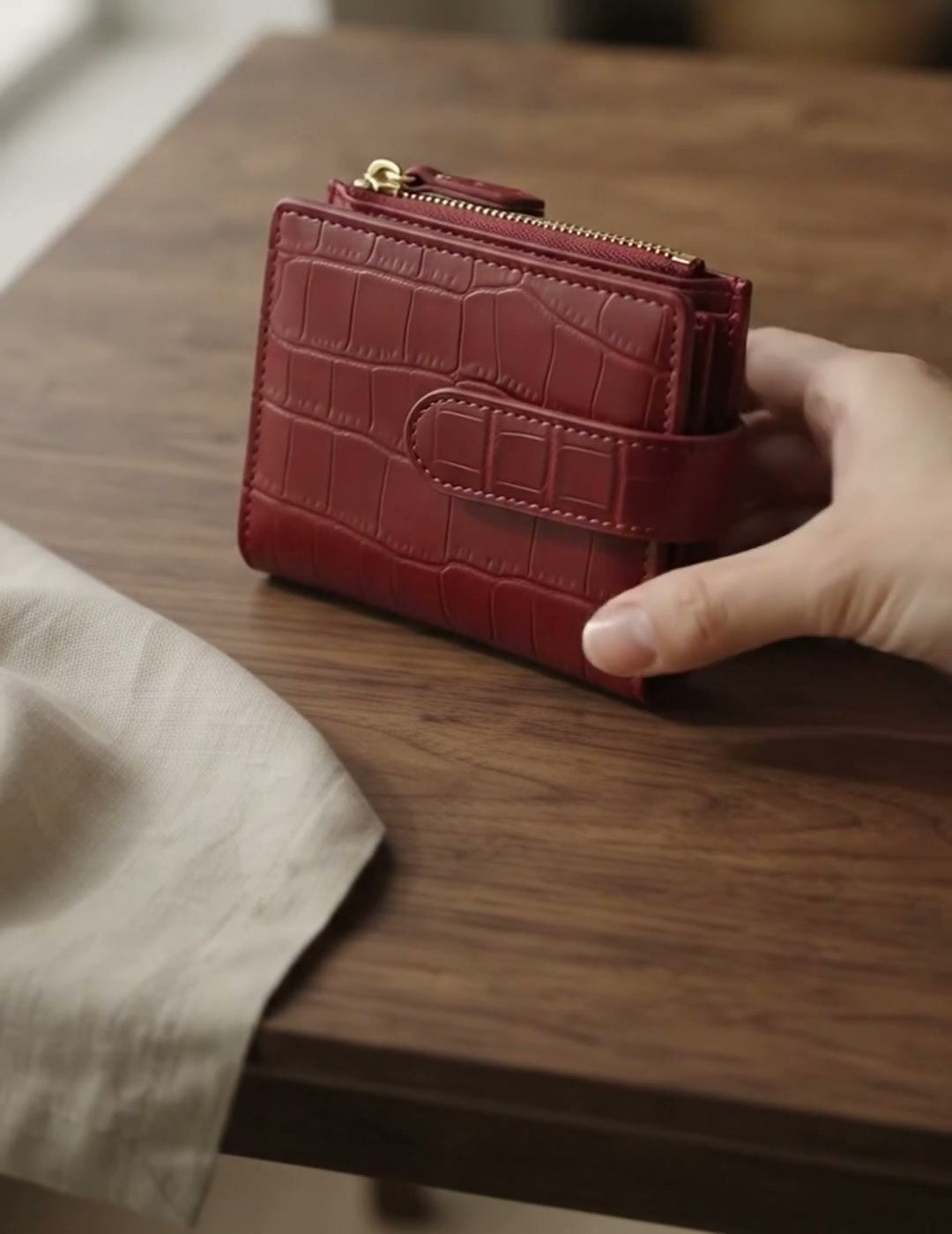 Wine red compact zip wallet held in hand